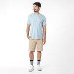 Man wearing a light blue t-shirt and beige shorts on a white background
