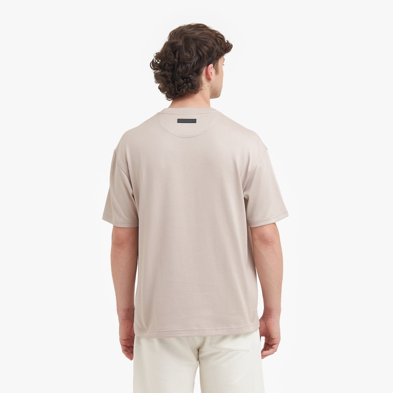 Back view of a man wearing a beige t-shirt on a white background