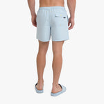A man is shown from the back wearing light blue swim shorts and matching slide sandals