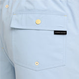 Close-up of a light blue shirt pocket with gold-tone snap buttons and a black James Bark brand label.