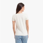 Back view of a woman wearing a plain white t-shirt and light blue jeans on a white background