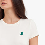 Close-up of a white t-shirt with a small green dinosaur design on a plain background