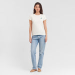 Woman wearing a white t-shirt with a logo and light blue jeans on a white background