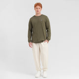 Full-length view of a man modeling a long-sleeved olive green t-shirt, off-white sweatpants, and white sneakers