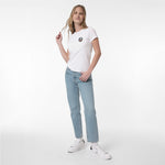 A woman modeling a white T-shirt with a small circular graphic on the left chest, paired with light-wash blue jeans