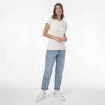 A woman modeling a T-shirt in off-white, paired with light-wash blue jeans and white sneakers