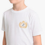 A child wearing a white short-sleeve crewneck t-shirt with a gold and navy blue emblem printed on the left chest.