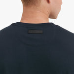 Close-up of a navy blue t-shirt with a brand label on the back against a white background