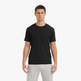 Man wearing a black t-shirt and gray pants on a white background