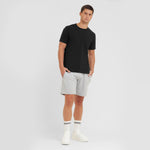 Man wearing a black t-shirt and gray shorts on a white background