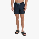 A man wearing dark navy blue swim shorts with a black waistband and a white drawstring, paired with black slide sandals