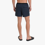 Back view of a man wearing dark navy blue swim shorts with a black waistband
