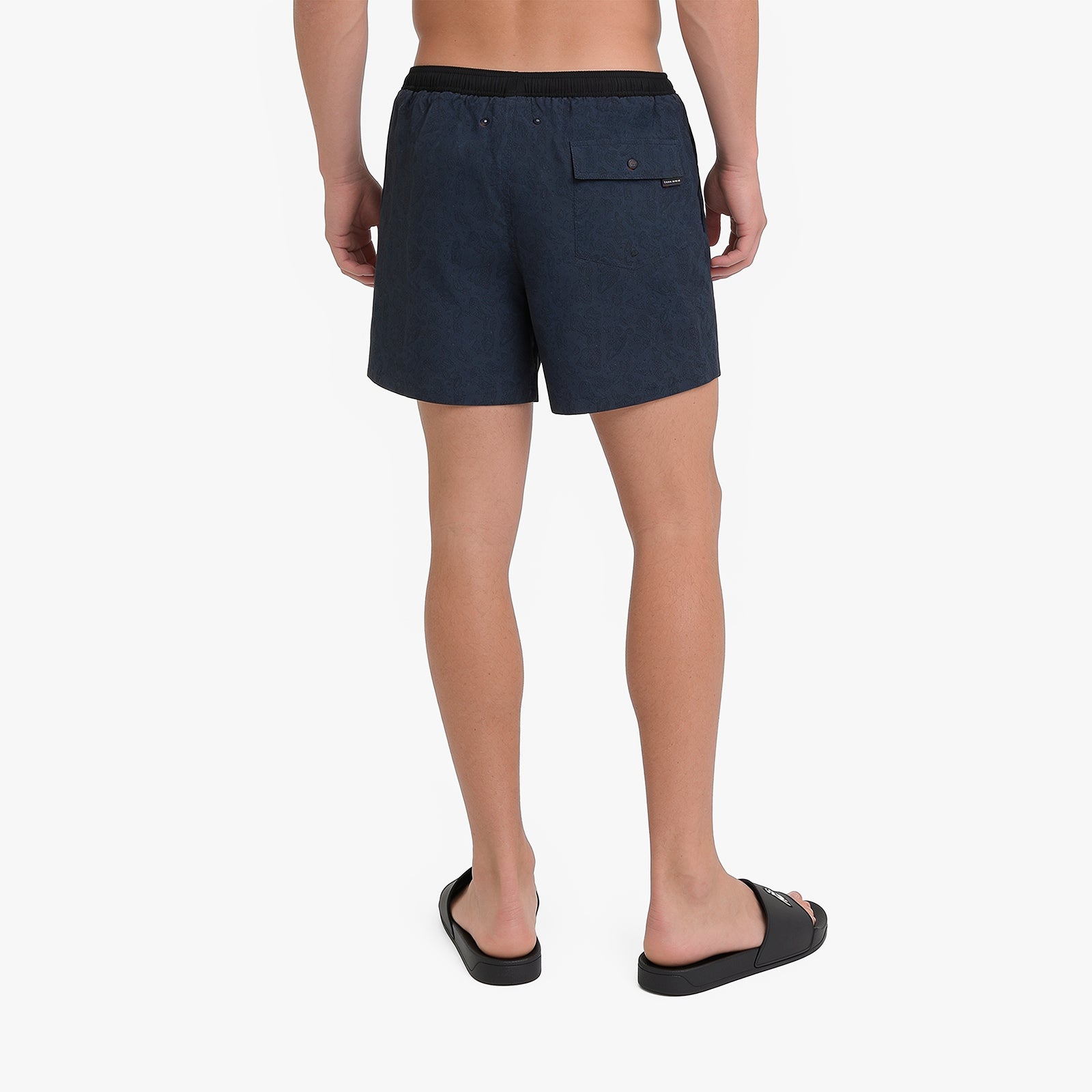 Back view of a man wearing dark navy blue swim shorts with a black waistband