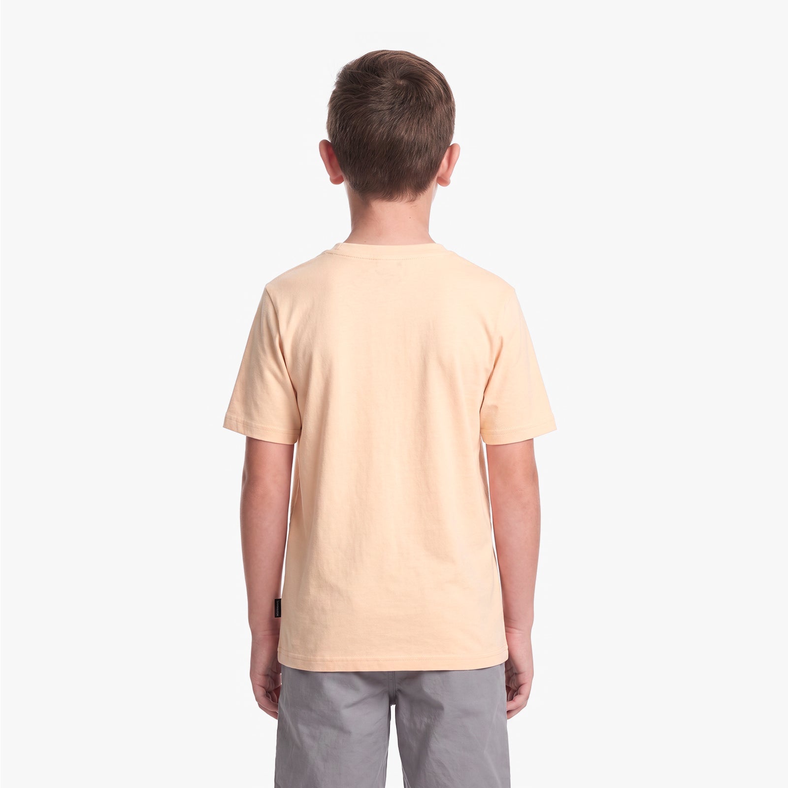 A child viewed from the back wearing a light peach T-shirt and gray pants, set against a white background.