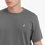 Close-up of a person wearing a gray t-shirt with a small logo on a white background