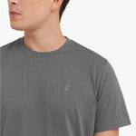 Close-up of a gray t-shirt with a small logo worn by a person on a white background