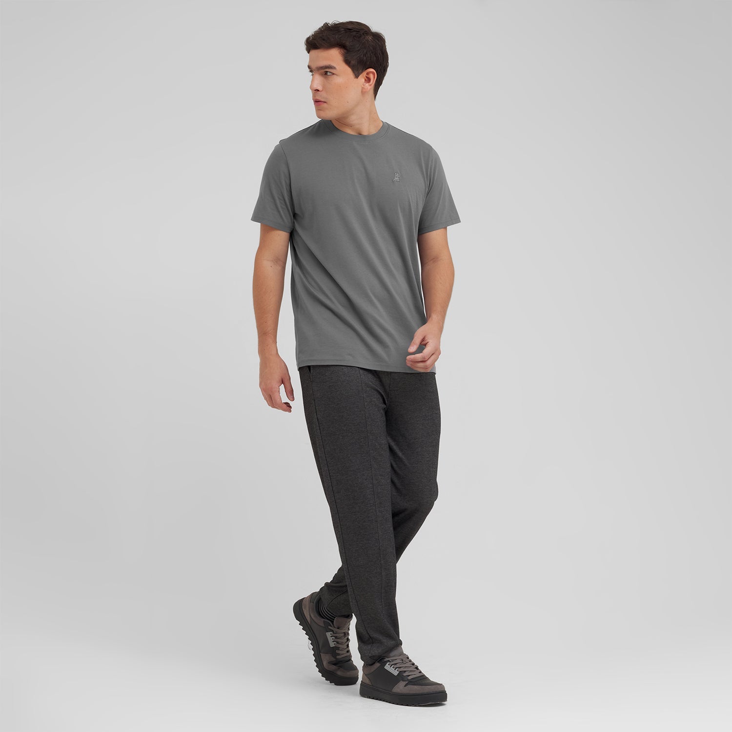 Man wearing a gray t-shirt and black pants on a light gray background