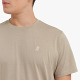 Close-up of a beige t-shirt with a small logo on a white background