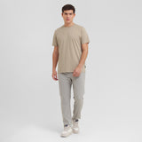 Man wearing a beige t-shirt and light gray pants on a white background
