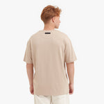 Back view of a man wearing a beige t-shirt on a white background