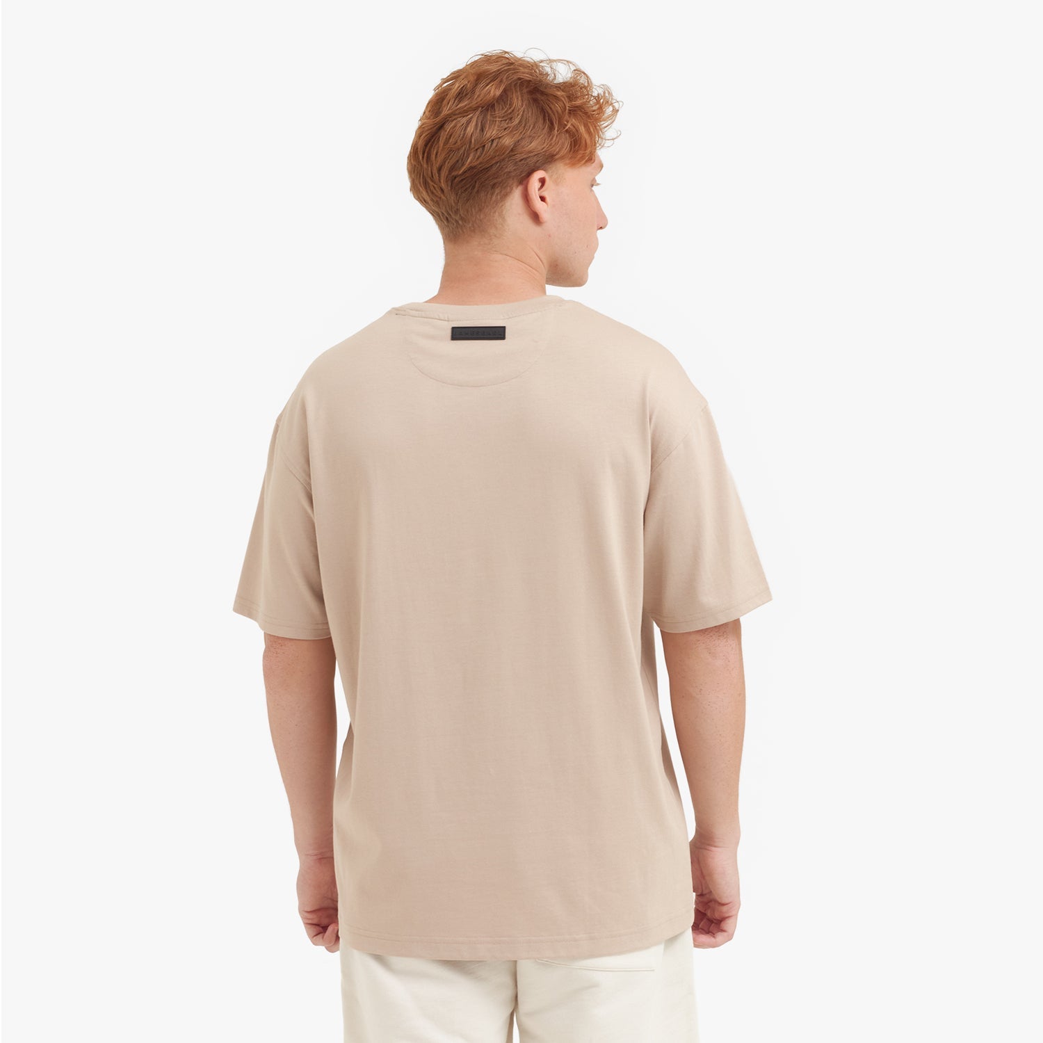Back view of a man wearing a beige t-shirt on a white background