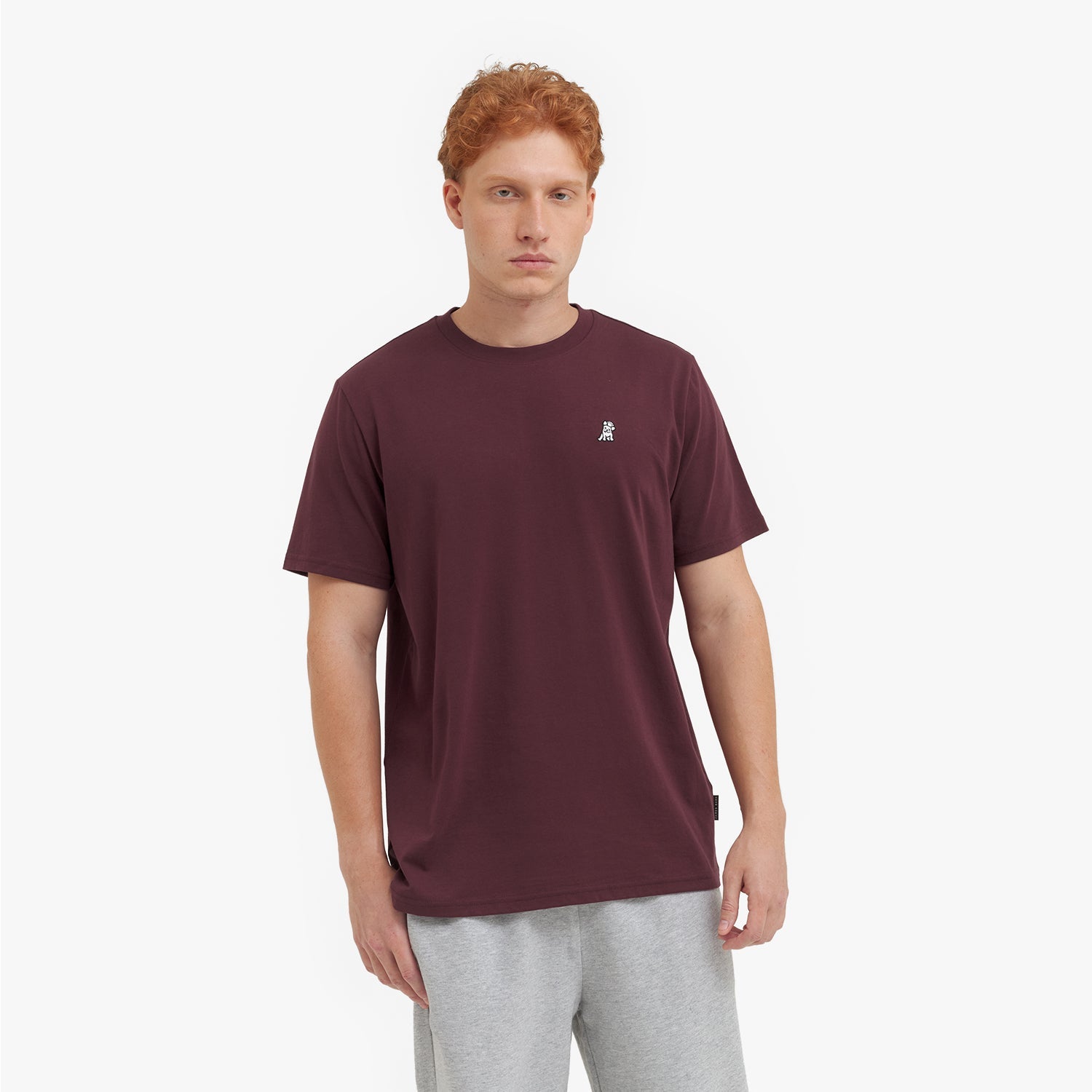 Man wearing a maroon t-shirt with a small logo on a white background