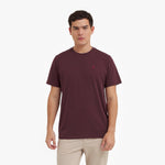 Man wearing a maroon t-shirt with a small logo on a white background