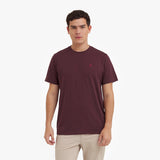 Man wearing a maroon t-shirt with a small logo on a white background