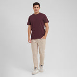 Man wearing a maroon t-shirt and beige pants on a white background
