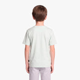 A child viewed from the back wearing a light green T-shirt and light gray pants