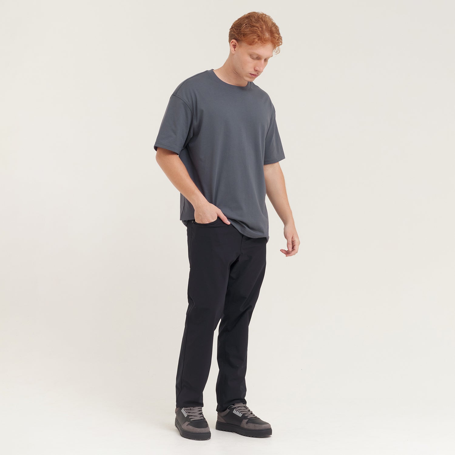 Man wearing a gray t-shirt and black pants on a white background