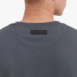 Close-up of a person wearing a dark gray shirt with a brand label on the collar.