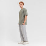 Person wearing a green t-shirt and gray pants on a white background