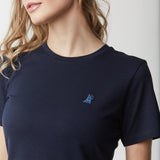 Close-up of the woman's upper body, highlighting the small embroidered logo on the chest of the navy blue t-shirt.
